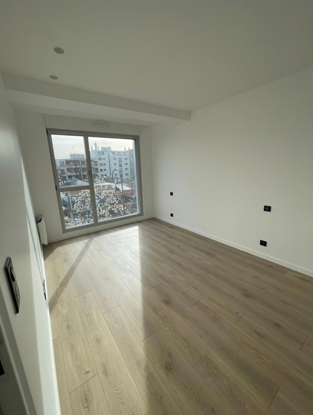 Salon rénové avec peinture claire et parquet moderne à Saclay